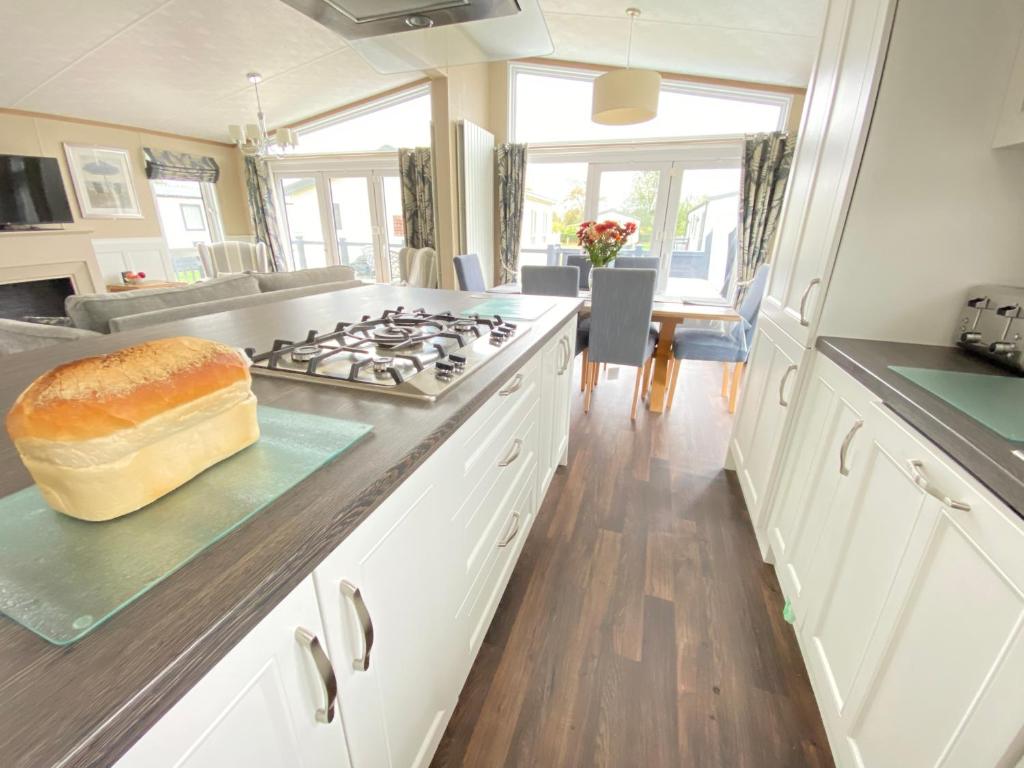 a kitchen with a stove with a loaf of bread on the counter at Wildflower, Premium Plus Hot Tub Lodge in South Cerney
