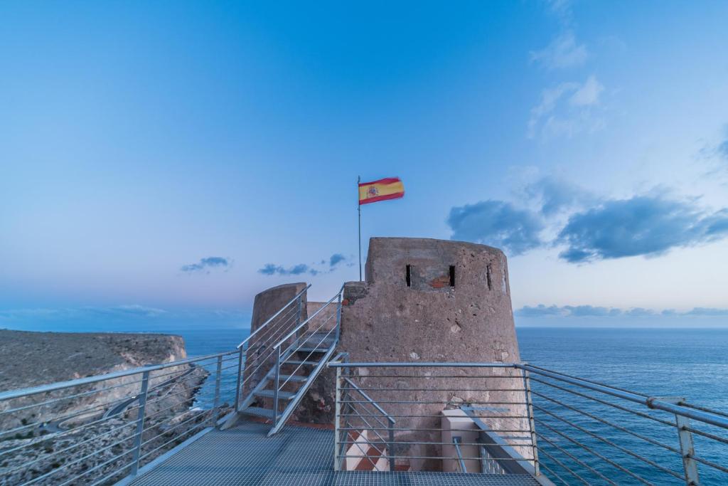 un edificio con una bandera en la parte superior del océano en Mirador Torre de la Garrofa, en Almería