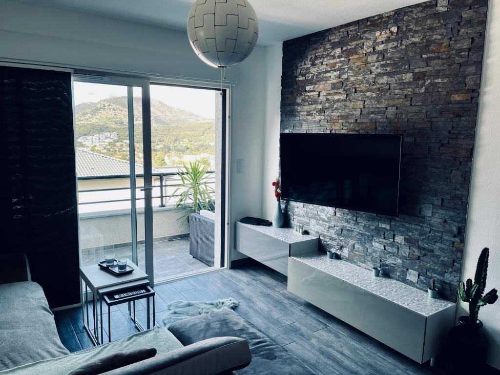 a living room with a tv and a brick wall at Casa Petra SALGA in Corte