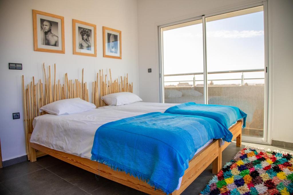 a bedroom with a bed with blue sheets and a window at Pure apartments in Taroudant
