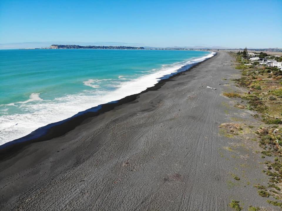 an aerial view of a black beach with the ocean at Napier Beach Top 10 Holiday Park & Motels in Napier