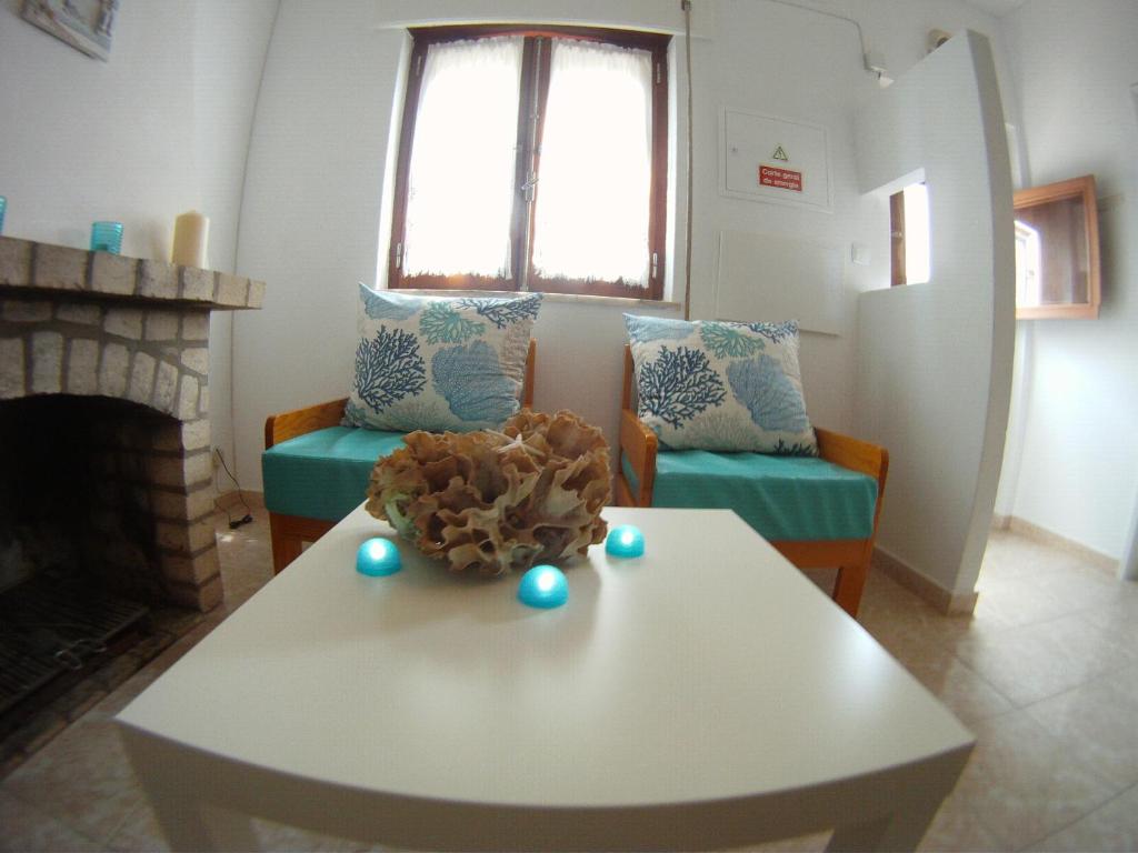 a living room with a white table and a fireplace at Ahoy Porto Covo Hostel in Porto Covo