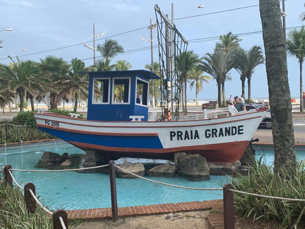 um barco sentado sobre rochas na água em APARTAMENTO NA PRAIA GRANDE A 200 MÉTROS DA PRAIA, CONFORTÁVEL ESPAÇOSO WIFI 350 Mega TV Claro, ÓTIMA LOCALIZAÇÃO na Praia Grande