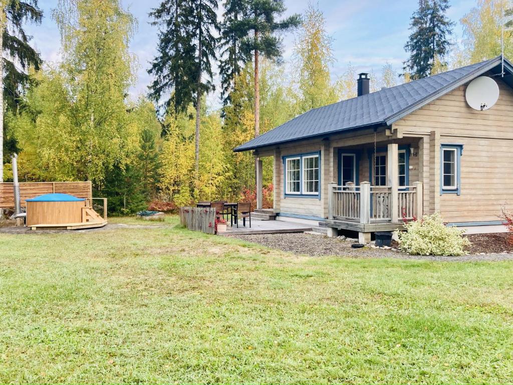 een klein huis met een veranda en een tuin bij Cottage Kivitatti in Sysmä
