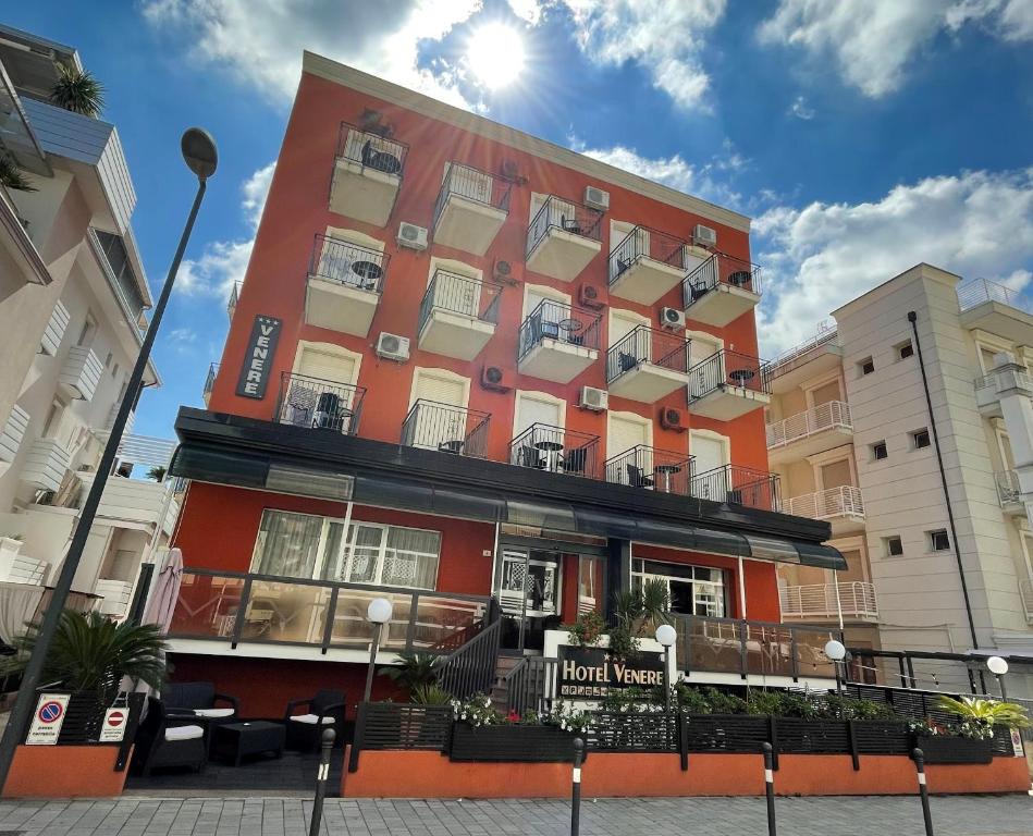 een oranje gebouw met een hotel naast twee gebouwen bij Hotel Venere in Rimini