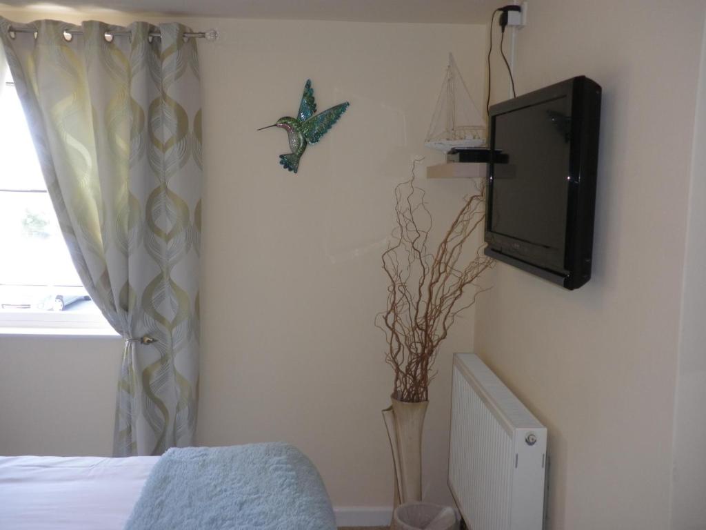 a bedroom with a tv on the wall next to a bed at Longfrie Inn in St. Saviour Guernsey