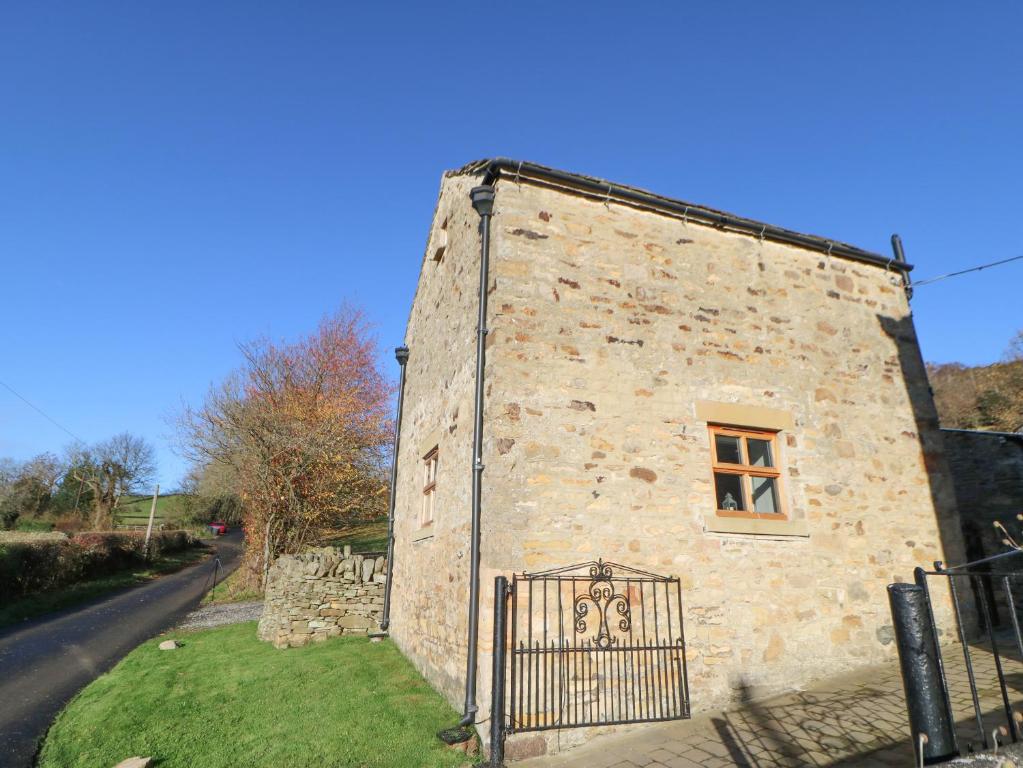 an old stone building with a window and a gate at Drover's Cottage in Wolsingham