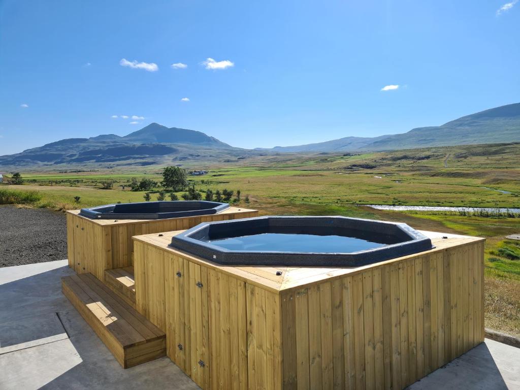 two hot tubs on a wooden deck with mountains in the background at Hlín Guesthouse in Varmahlid