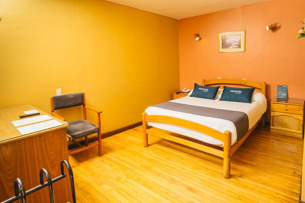 Schlafzimmer mit einem Bett, einem Schreibtisch und einem Stuhl in der Unterkunft Ayenda Posada San Juan in Arequipa