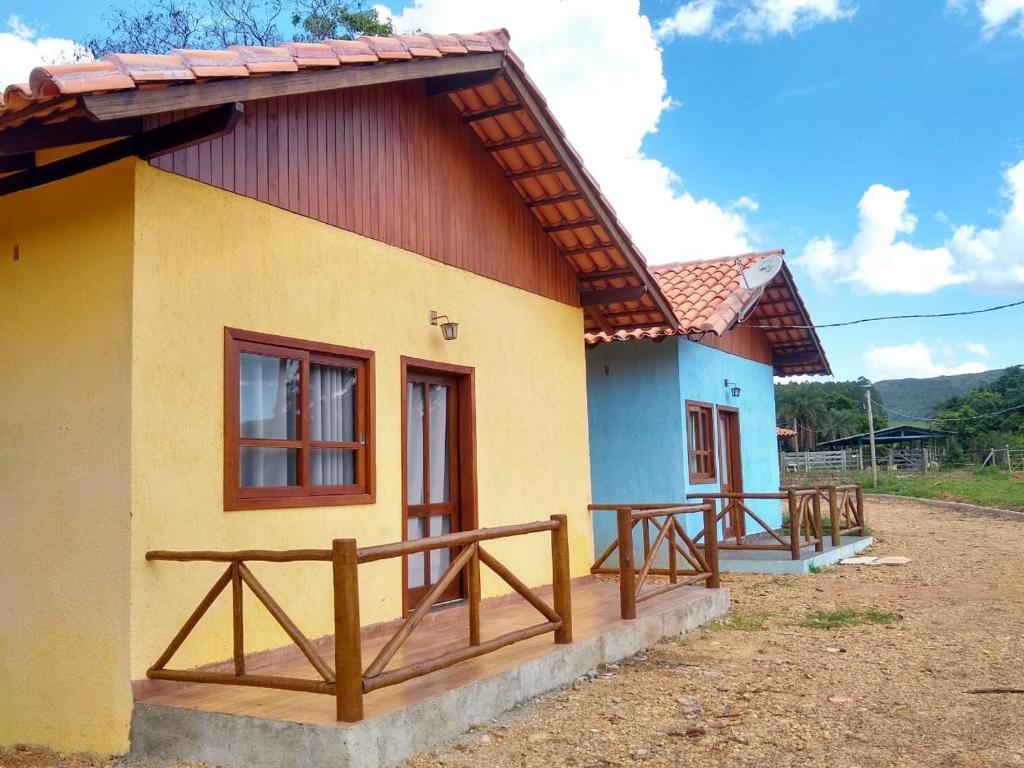 a small yellow and blue house with a wooden porch at Chalé Águas Claras in Capitólio