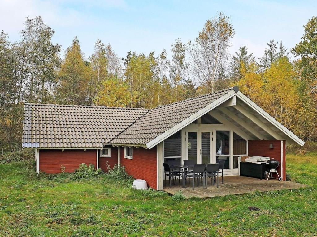 una casa rossa con un tavolo e sedie di fronte di 4 person holiday home in Martofte a Martofte