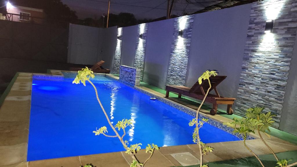 uma piscina azul com um banco ao lado de uma parede em Alojamiento El Jilguero em Puerto Iguazú