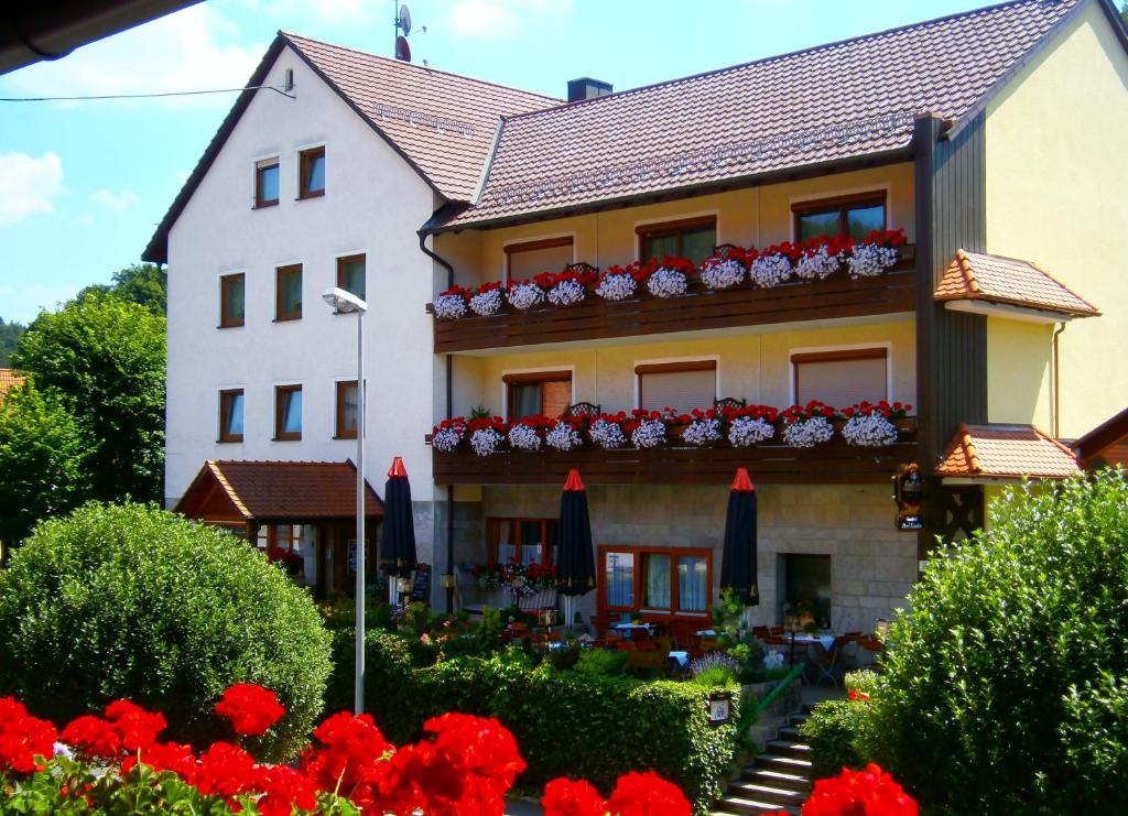 ein Gebäude mit roten Blumen davor in der Unterkunft Gasthof Drei Linden in Obertrubach