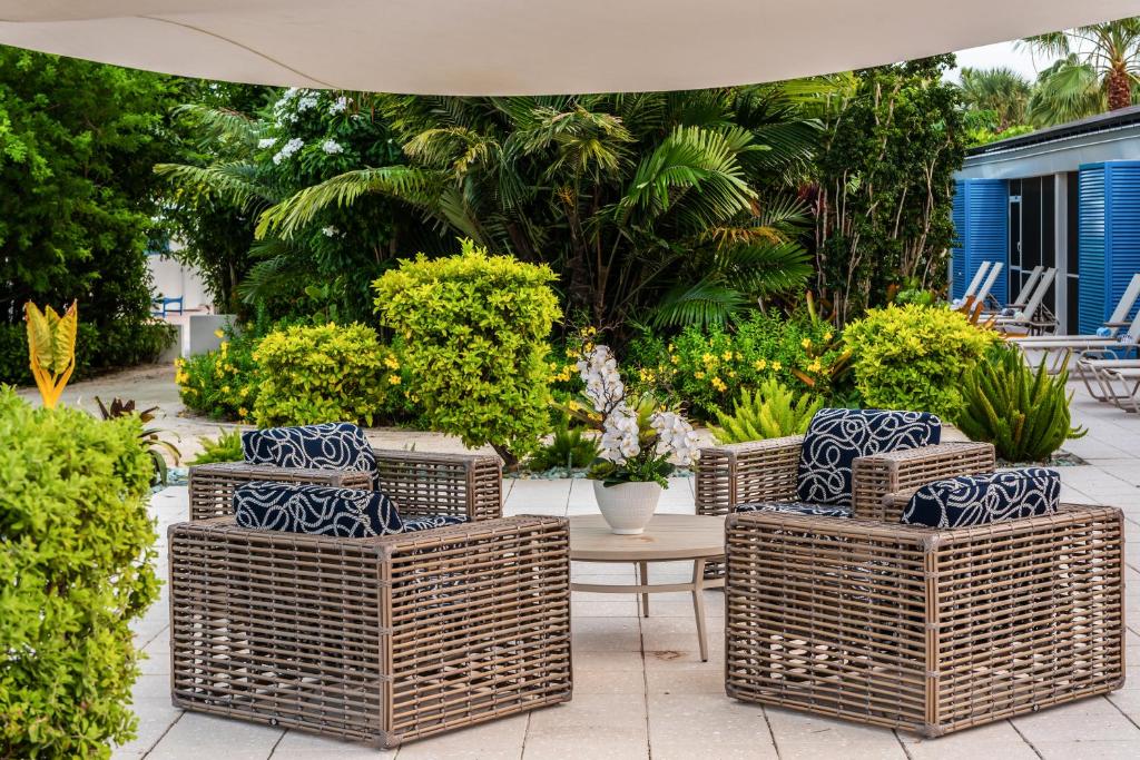 a group of wicker chairs and a table in a garden at Islander Resort in Islamorada