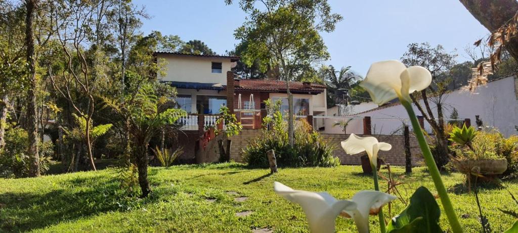 una casa con un patio con flores blancas en primer plano en Chácara da Promessa de Deus, en Icatuaçu