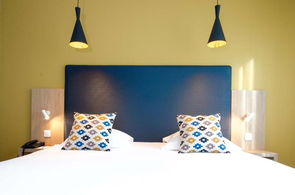 two beds in a room with two pillows at Best Western Plus Hotel Plaisance in Villefranche-sur-Saône