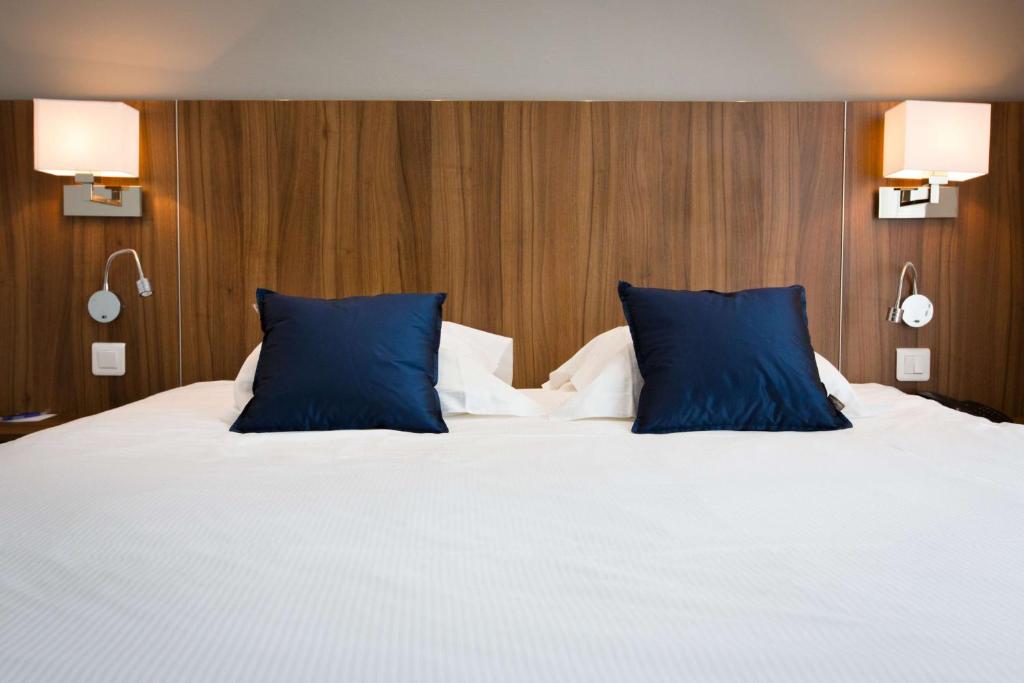 un grande letto con cuscini blu in una camera da letto di Best Western Plus Hotel Plaisance a Villefranche-sur-Saône