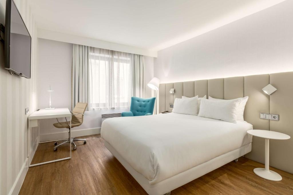 Habitación de hotel con cama blanca grande y escritorio. en NH Brussels Grand Place Arenberg, en Bruselas