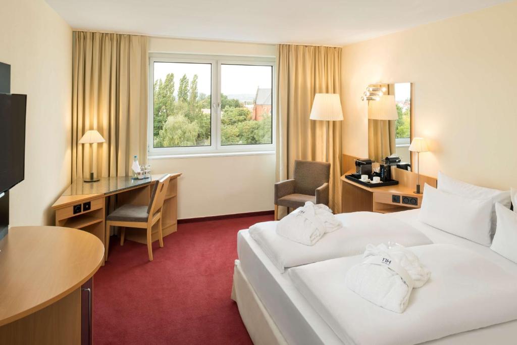 a hotel room with a bed and a desk at NH Dresden Neustadt in Dresden