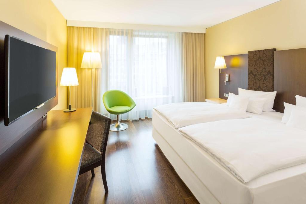 a hotel room with two beds and a flat screen tv at NH Collection Dresden Altmarkt in Dresden