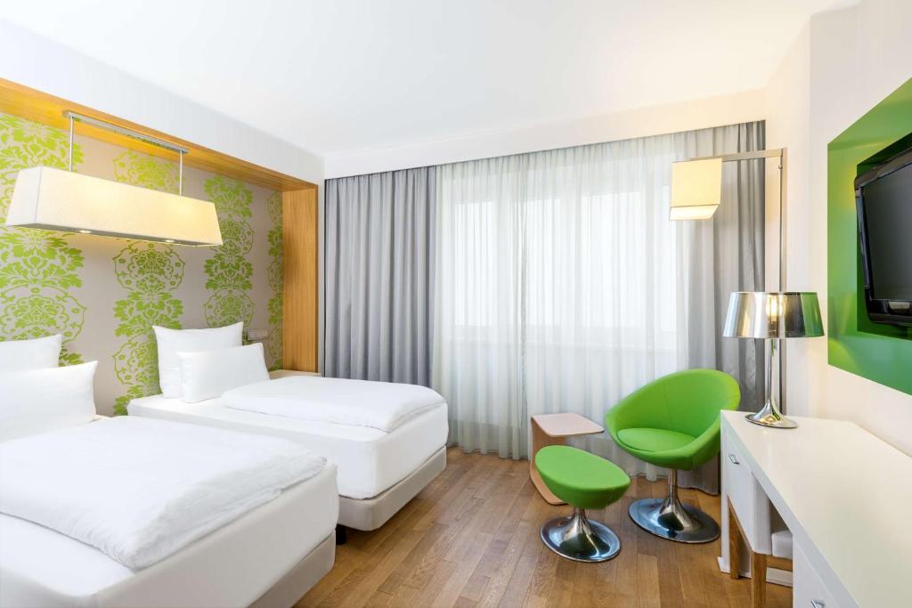 a room with a bed, chair, desk and a lamp at NH Frankfurt Messe in Frankfurt