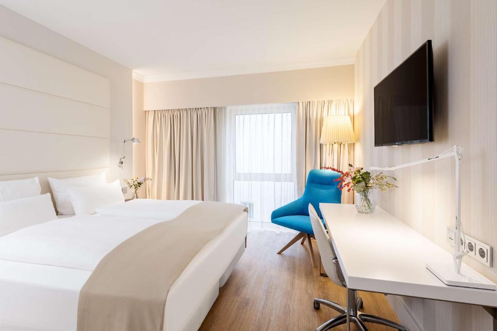 a hotel room with two beds and a desk at NH Hamburg Mitte in Hamburg
