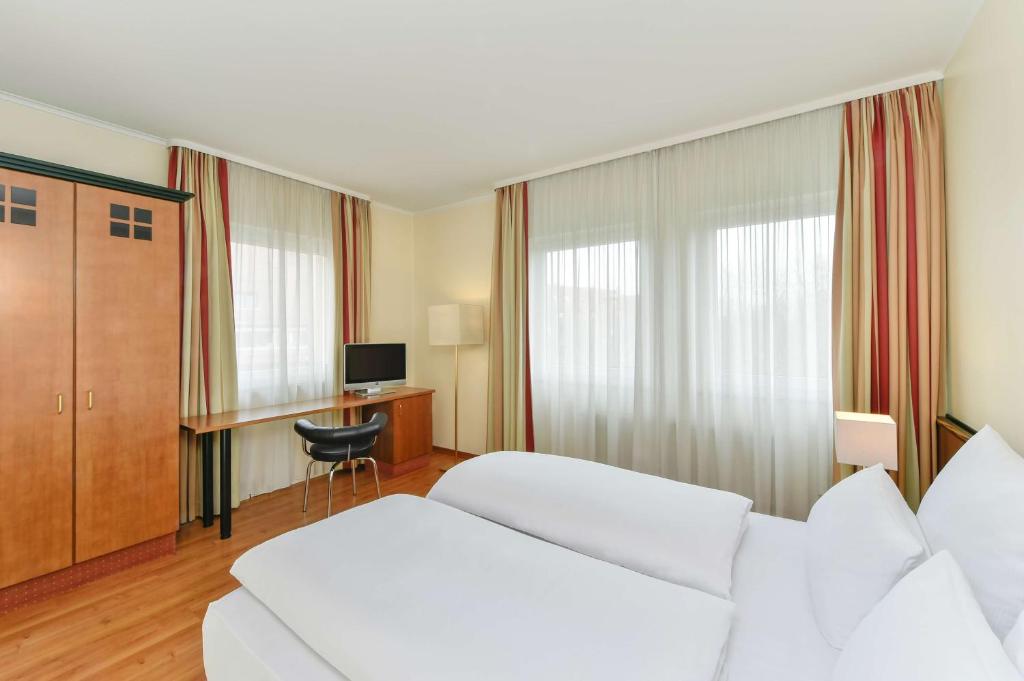 a hotel room with two beds and a desk at NH München City Süd in Munich