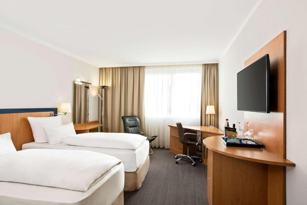 a hotel room with two beds and a desk at NH Frankfurt Airport West in Raunheim