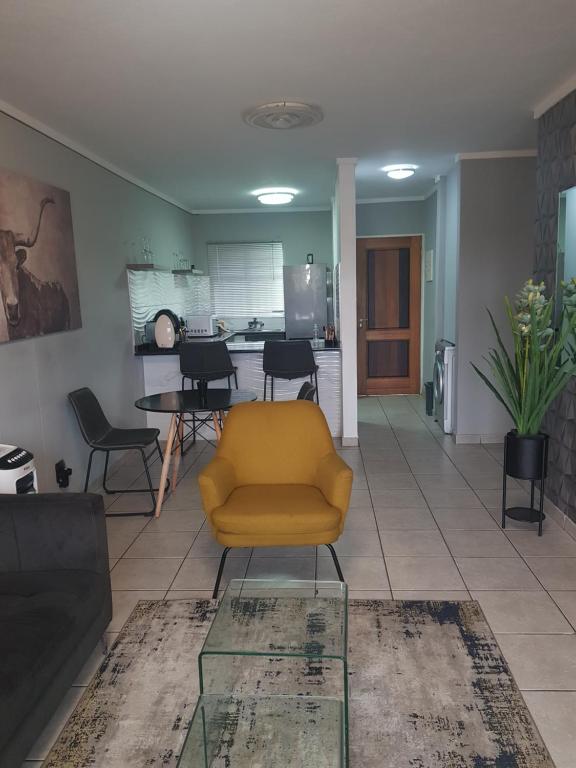 a living room with a yellow chair and a kitchen at Menlyn Place in Pretoria