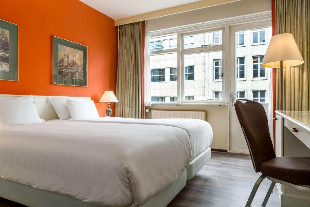 a hotel room with a large bed and a window at NH Atlanta Rotterdam Hotel in Rotterdam