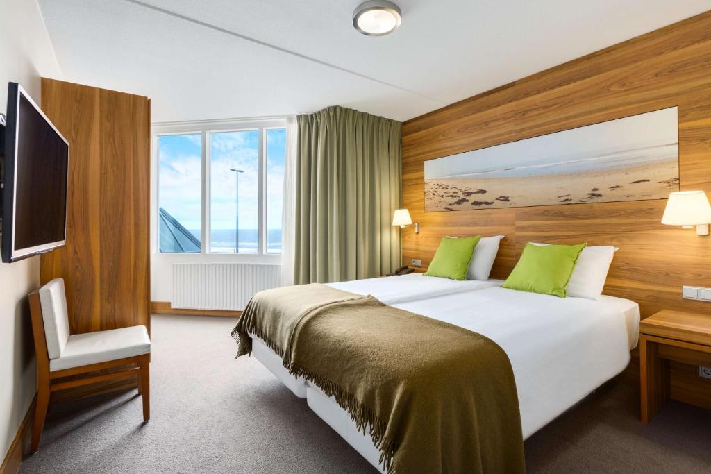 een hotelkamer met een groot bed en een televisie bij NH Zandvoort Hotel in Zandvoort