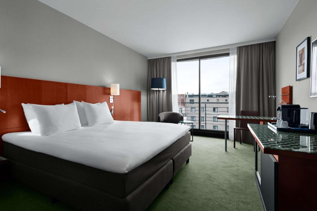 a hotel room with a bed and a large window at NH Brussels EU Berlaymont in Brussels