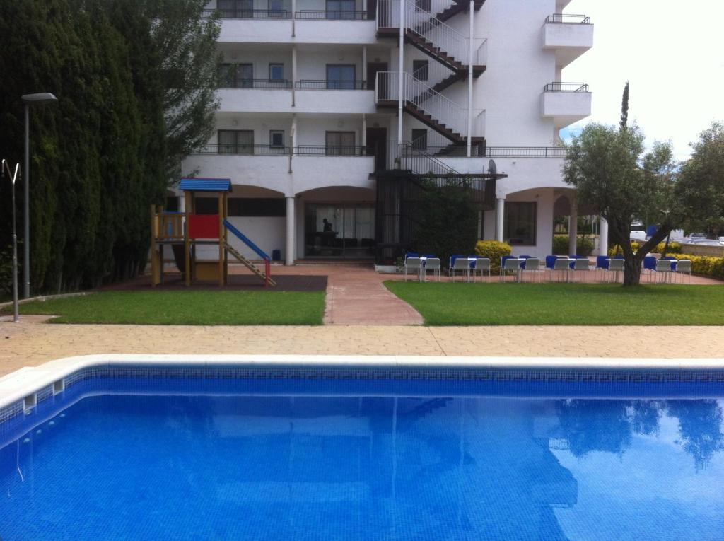 uma piscina azul em frente a um edifício em Bay Hotel em Roses