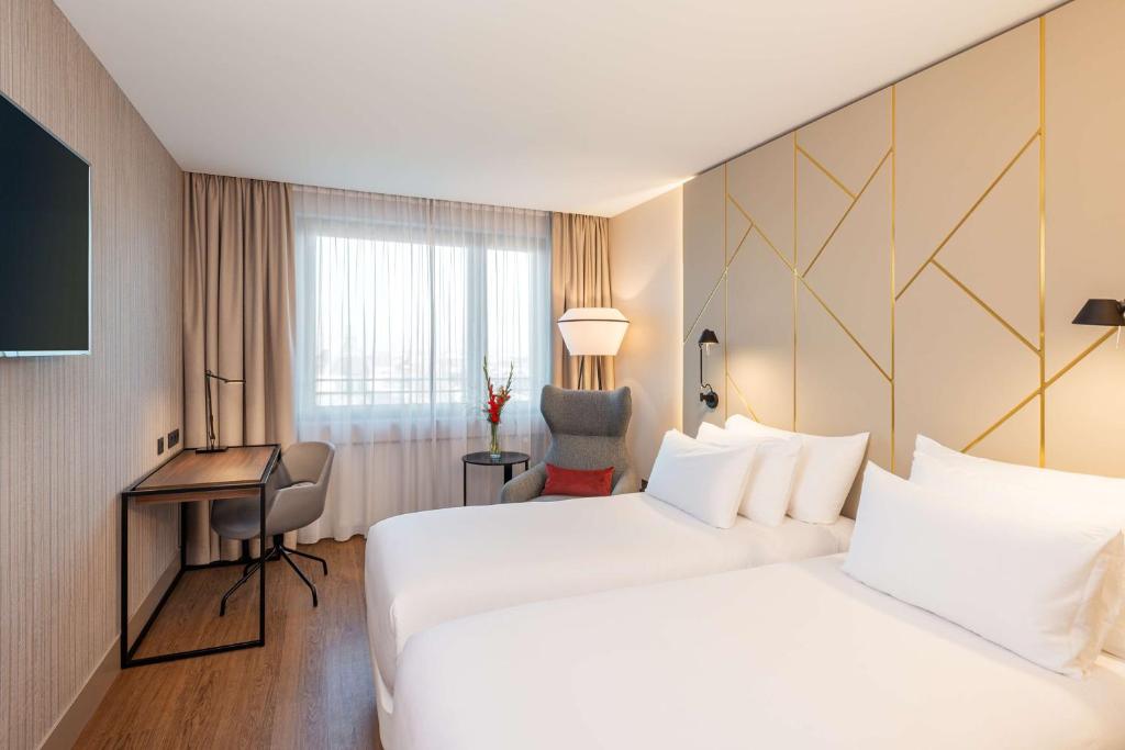 a hotel room with two beds and a desk at NH Collection München Bavaria in Munich