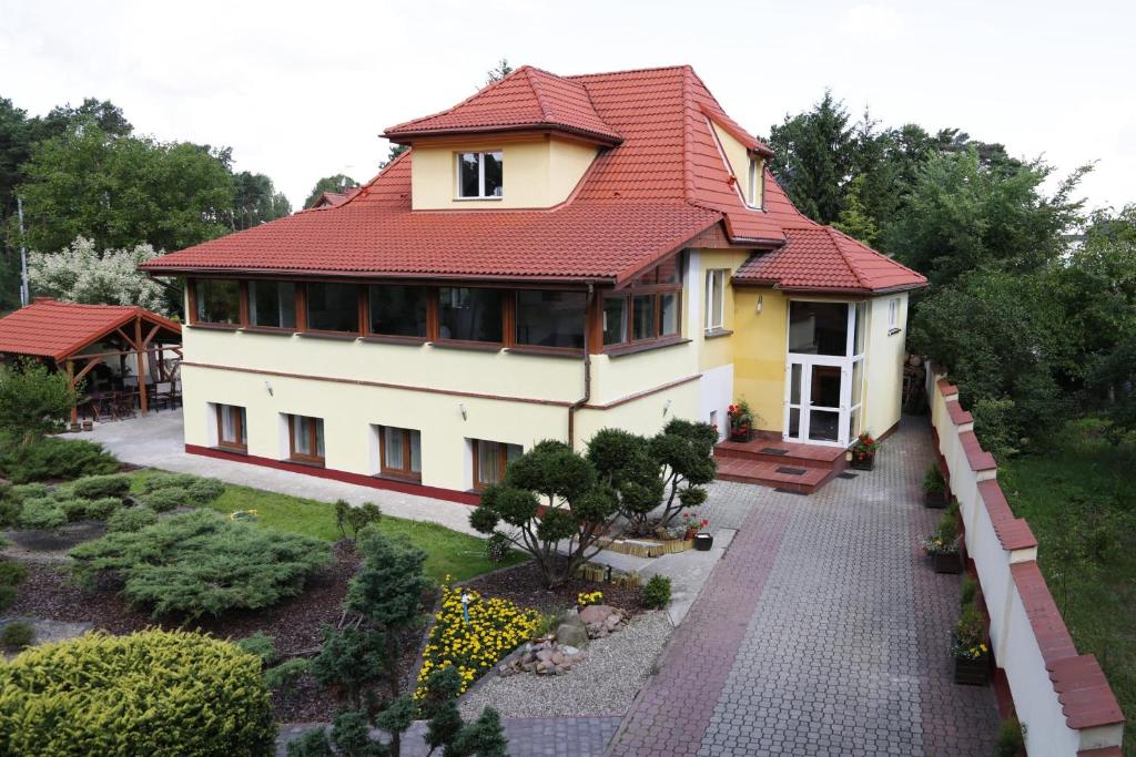 uma casa com um telhado vermelho e um jardim em WIlla Maksymilian Bed and Breakfast em Bydgoszcz