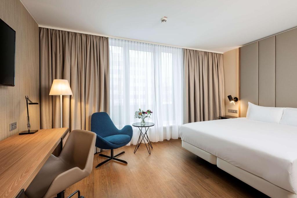 ハノーファーにあるNH Hannoverのベッド、デスク、椅子が備わるホテルルームです。