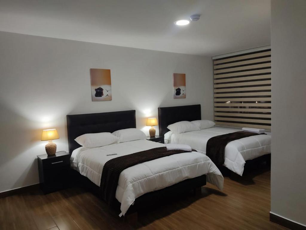 a hotel room with two beds and two lamps at Hospedaje El Girasol TABABELA in Quito