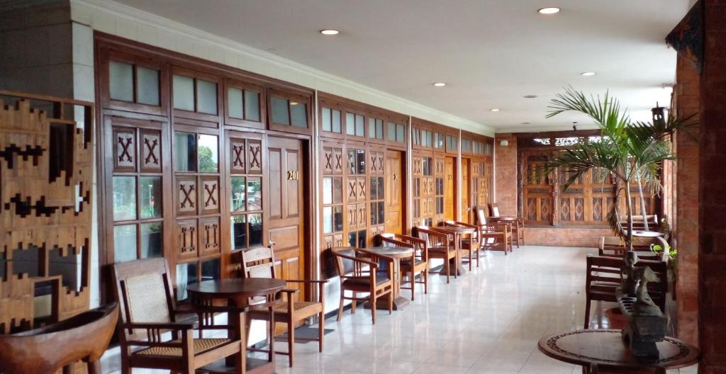 a restaurant with wooden tables and chairs and windows at Hotel Bifa Yogyakarta in Yogyakarta