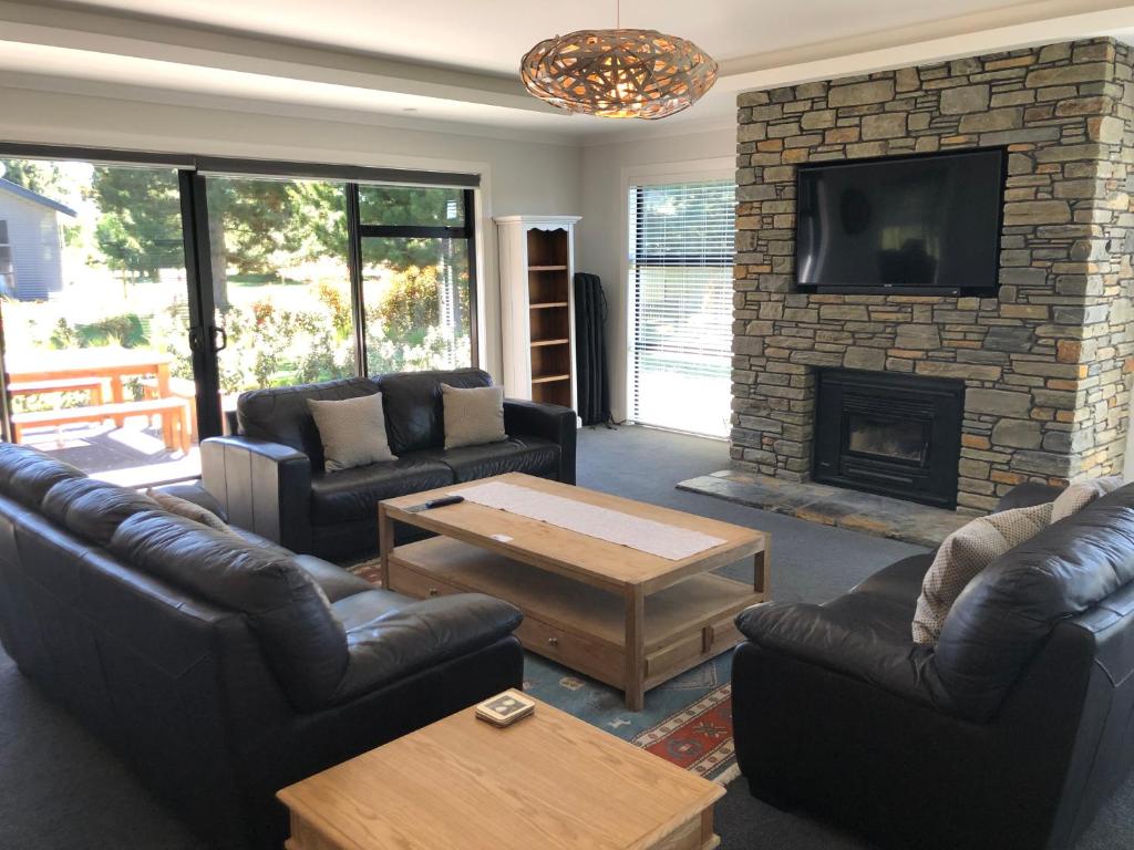 a living room with couches and a brick fireplace at 4 Bedroom on North West Arch - Free Wifi in Twizel