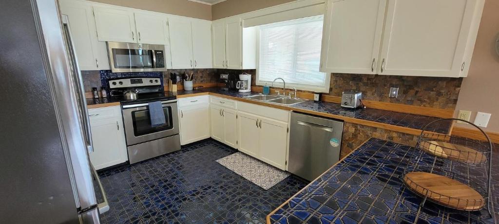 cocina con armarios blancos y suelo de baldosa azul en Large Home Sunset Dreams off Bay - Madre Azul Bay House, en South Padre Island