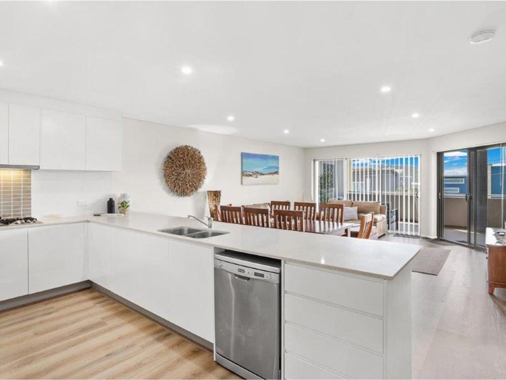 a kitchen with white cabinets and a dining room at Villa Serene 3 in Fingal Bay