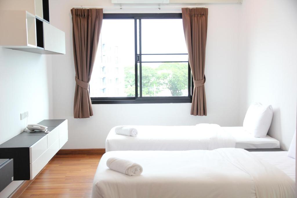 a living room with two beds and a window at V-twin Donjan Service Apartment in Chiang Mai