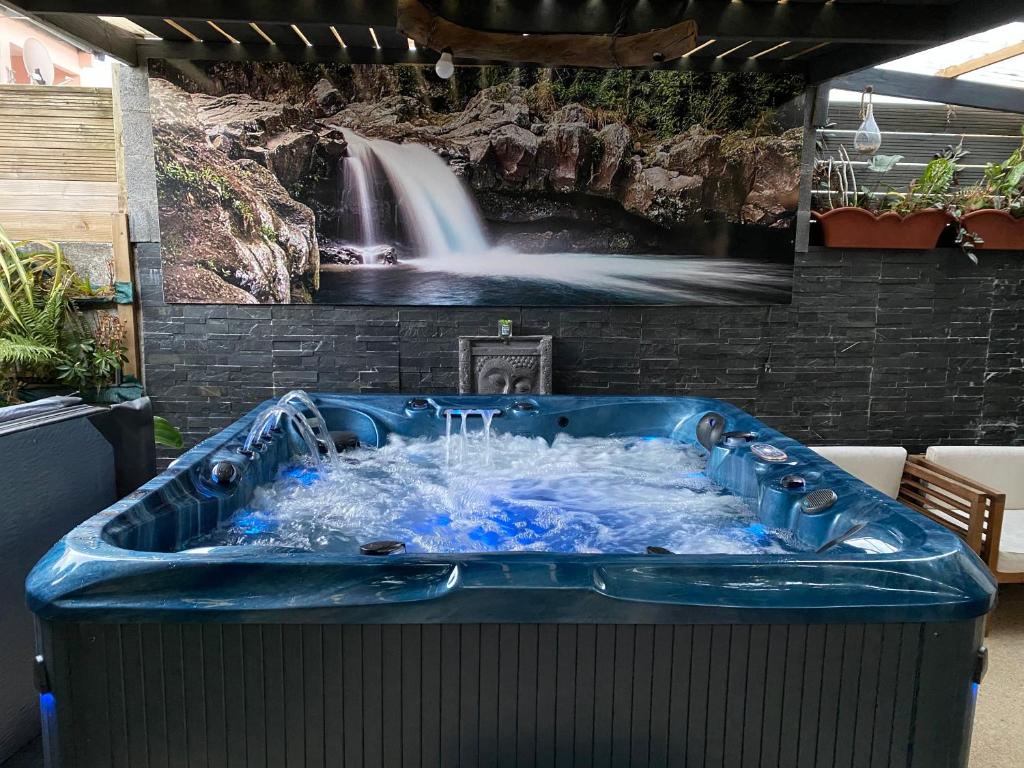 a large blue bath tub with a waterfall on a wall at Fleur des iles in Bras-Panon
