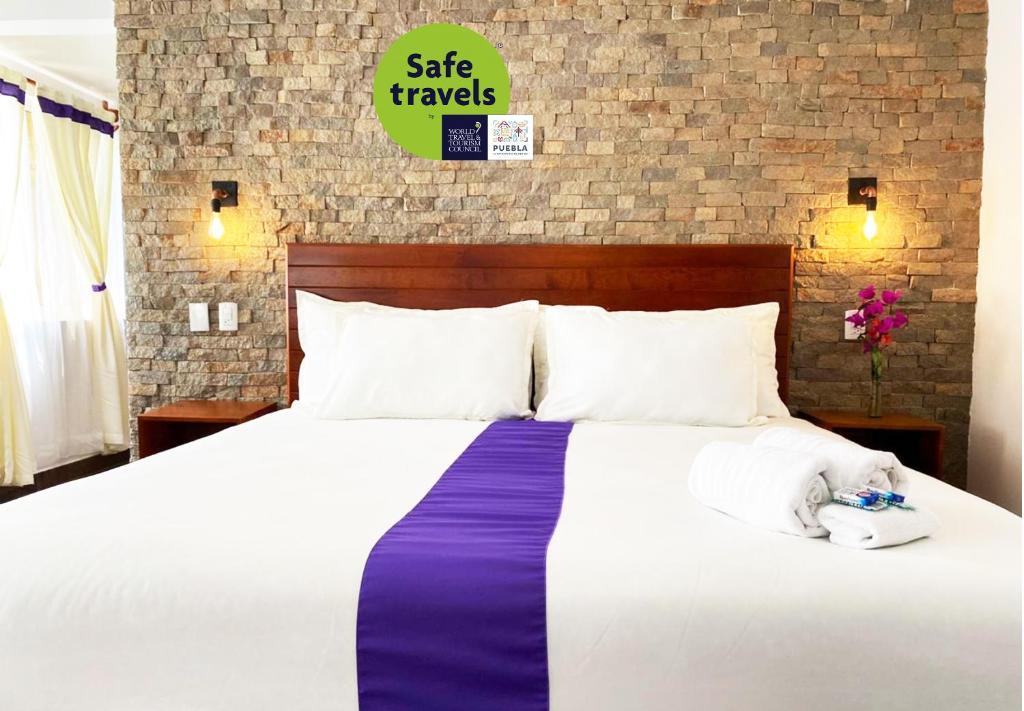een slaapkamer met een groot wit bed en een paarse deken bij Hotel & Suites Cerro Roj0 in Tlatlauquitepec