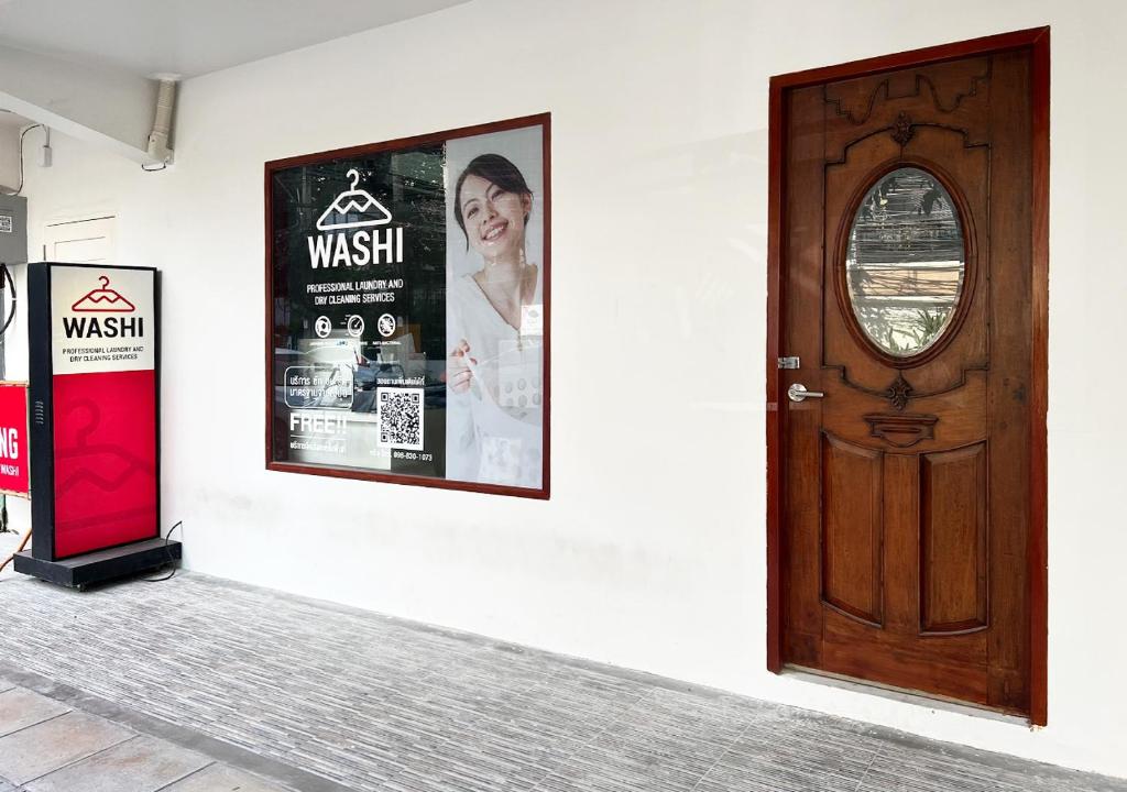 a wooden door on a white wall with posters at Niagara Hotel in Bangkok