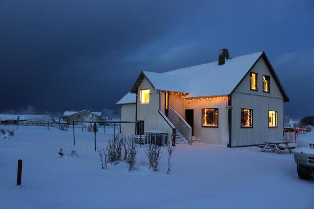 Una casa iluminada en la nieve por la noche en Guesthouse Hateigi 2, en Hella