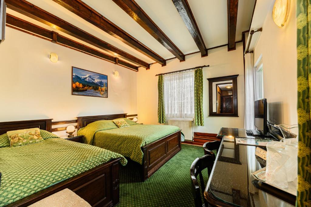Cette chambre comprend deux lits et une télévision. dans l'établissement Pension Casa Bradul, à Predeal