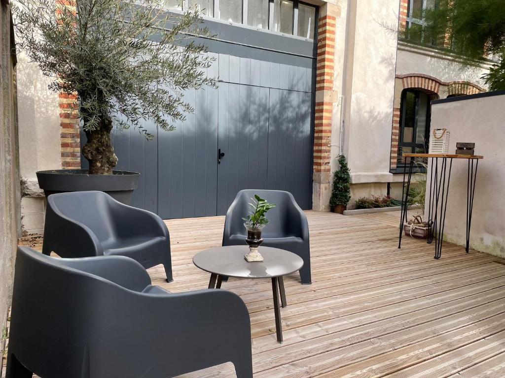 a patio with chairs and a table and a blue garage door at Maison d'hotes L'atelier du Charmois in Vandoeuvre-lès-Nancy