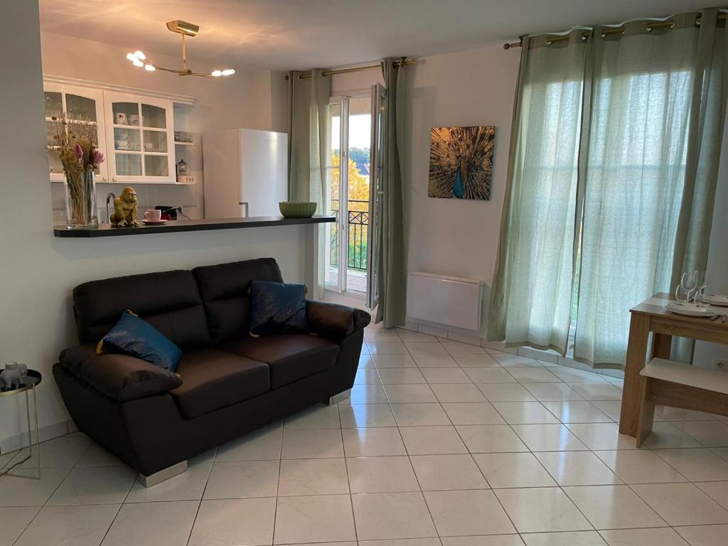 a living room with a brown couch and a kitchen at Charmant appartement duplex à 5min de Disney. in Magny-le-Hongre