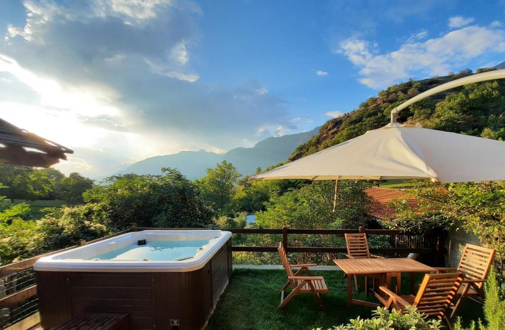 een hot tub met een tafel en stoelen en een parasol bij il Battito in Saint Vincent